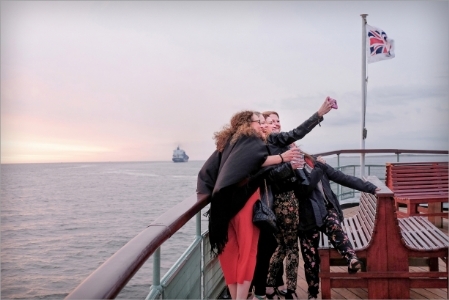 Girls taking a selfie near the bow of a cruise boat.