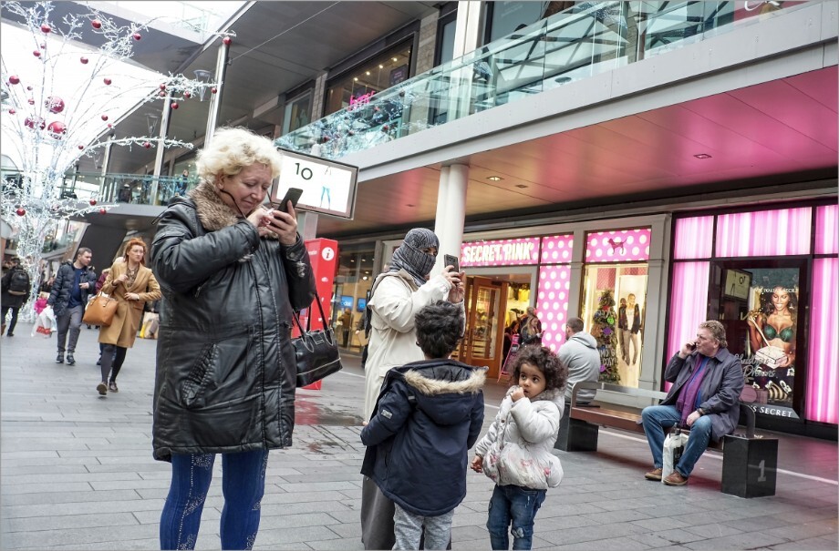 wo women of different nationalities absorbed in their phones to the bewilderment of the children.