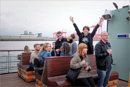 People enjoying a cruise on top deck of a ferry boat on the River Mersey