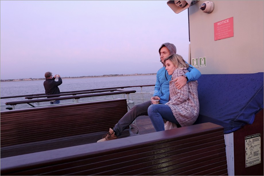 A couple hug as they watch the sunset from the top deck of a Mersey ferryboat during an evening cruise.