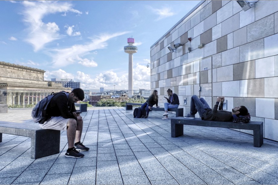Young adults relax with theit mobile phones on the rooftop of the remodelled Liverpool Central library.