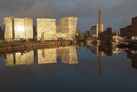 Modern buildings reflected in the calm water of a disused dock.